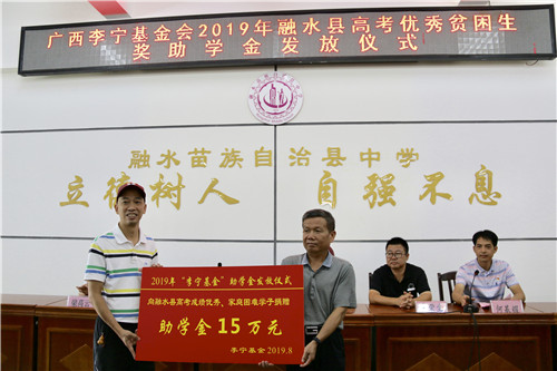2、融水苗族自治县政协副主席何来源(右)与广西李宁基金会副秘长林志强举行受助金交接仪式