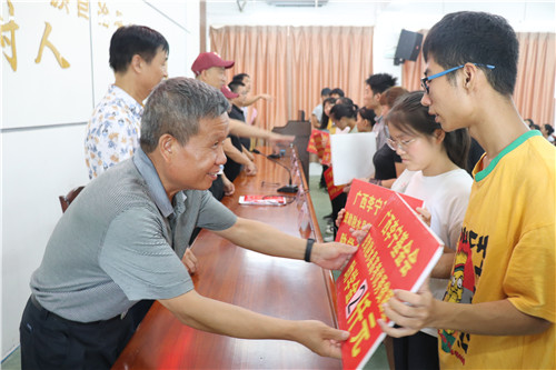 5、融水苗族自治县政协副主席何来源(左)给受助学生发放助学金
